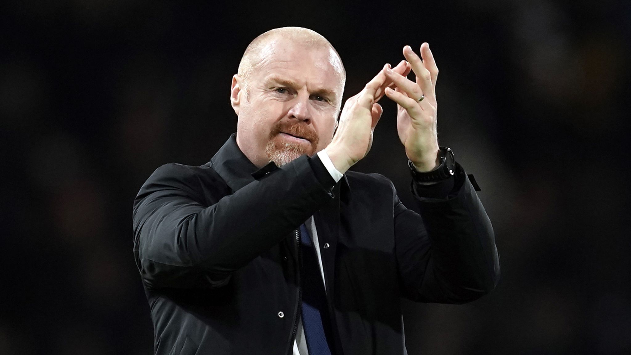 Sean Dyche holding a Nottingham Forest jersey at his unveiling as Head Coach, standing beside club executives in a press conference setting.